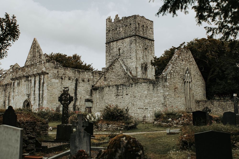 Stone ruins of an ancient ecclesiastical church with gothic arches and overgrown vegetation in a tranquil setting.