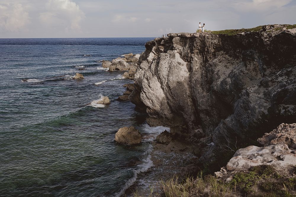 Rocky limestone cliffs rise dramatically above turquoise Mediterranean waters along a rugged coastal shoreline.