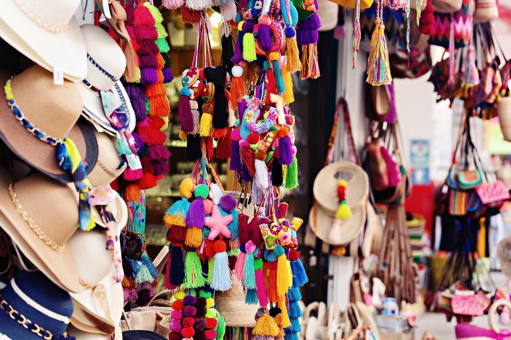 Colorful handmade decorative tassels and ornaments hanging at market stall display vibrant crafts and souvenirs.