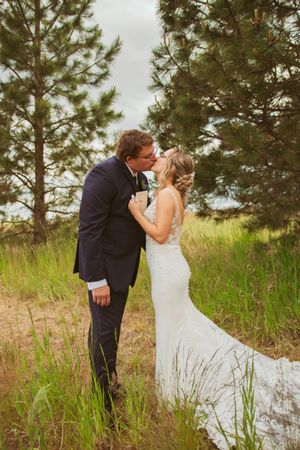 A couple shares a joyful first look moment on their wedding day in a rustic outdoor setting with pine trees.