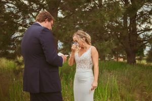 A couple shares an emotional moment during their wedding in a field of tall grass at sunset.