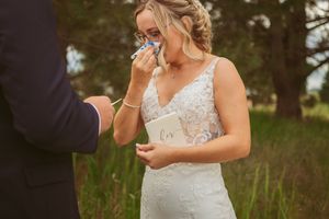 An emotional moment during a wedding ceremony with someone wiping away tears while wearing an elegant lace wedding gown.