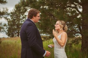 A romantic first look unfolds between newlyweds in a natural outdoor setting with evergreen trees.