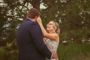 A dance sequence between a couple in formal attire captured in a grassy field beside evergreen trees.