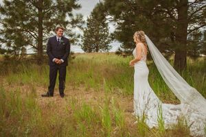 Flowing white wedding dress and veil create movement against a scenic mountain landscape with evergreens.