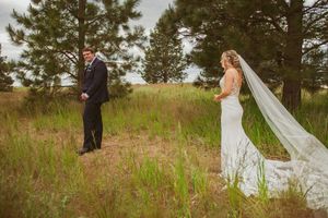 A wedding couple shares tender moments during their outdoor photo session among pine trees and tall grass.