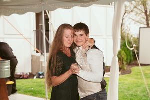 A couple shares an intimate slow dance moment under draped white tent fabric at a wedding reception.