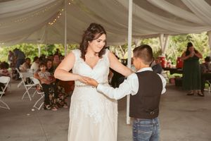 Dancers moving and embracing on the dance floor at an outdoor tented wedding reception.