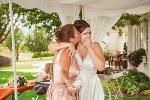 Wedding guests gather under an elegant white tent decorated with floral arrangements and soft lighting.