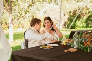 Couple shares an intimate moment while dining at a decorated outdoor table with floral arrangements.