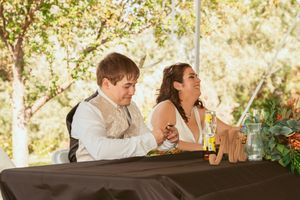 A couple sitting at an outdoor table laughs together during a summer gathering at sunset.