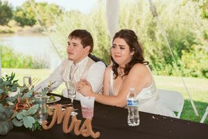 Wedding reception table decorated with eucalyptus garlands and 'Mr & Mrs' sign under outdoor tent.