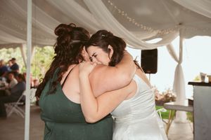 A romantic couple shares a tender dance beneath white fabric draping at an elegant outdoor wedding reception.