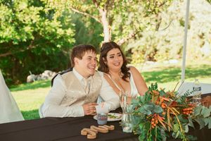 Wedding guests enjoy an outdoor reception dinner under string lights and greenery in a garden setting.