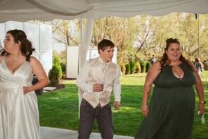 Wedding guests dancing and celebrating under a tent with decorative draping.