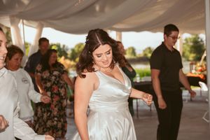 Celebratory dancing moment under an elegant white wedding tent with draped fabric.