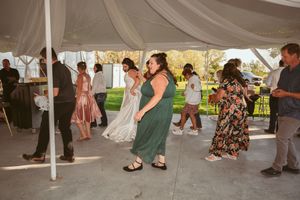 Wedding celebration under a white tent with guests dancing and mingling on a patio outdoors.
