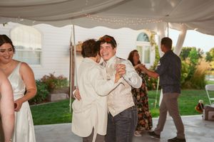 Joyful dancing and celebration under a white tent at a wedding reception.
