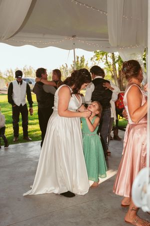 Wedding celebration under a white tent with dancers in elegant dresses enjoying the festivities on the dance floor.