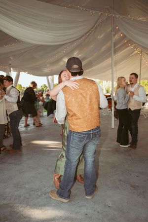 Couples slow dancing under a draped tent ceiling with twinkling lights at an outdoor wedding reception.