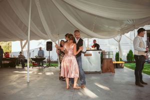Couples slow dancing under a white tent at an outdoor afternoon wedding reception.