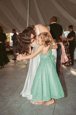 Bridesmaids in mint green and white dresses dancing in formation on a dance floor under a tent.