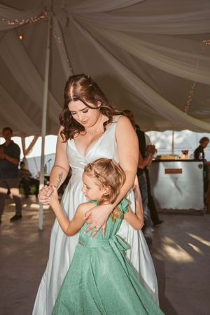 A tender dance moment between two people in a white and mint green dress under a draped tent ceiling at an event.