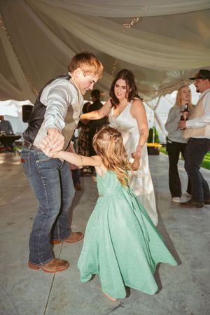 Dancing under a draped tent at a wedding reception with someone in a mint green dress twirling and swaying to the music.