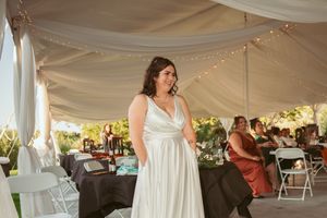 Wedding celebration under elegant white tent decorated with string lights and draping.