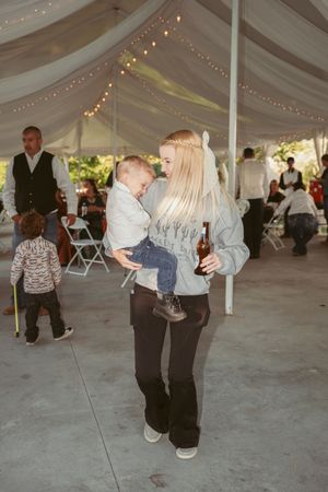 Wedding guests enjoying dances under a decorated tent with string lights.