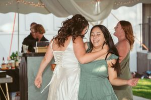 Wedding guests dance and celebrate on a dance floor during an indoor reception celebration.