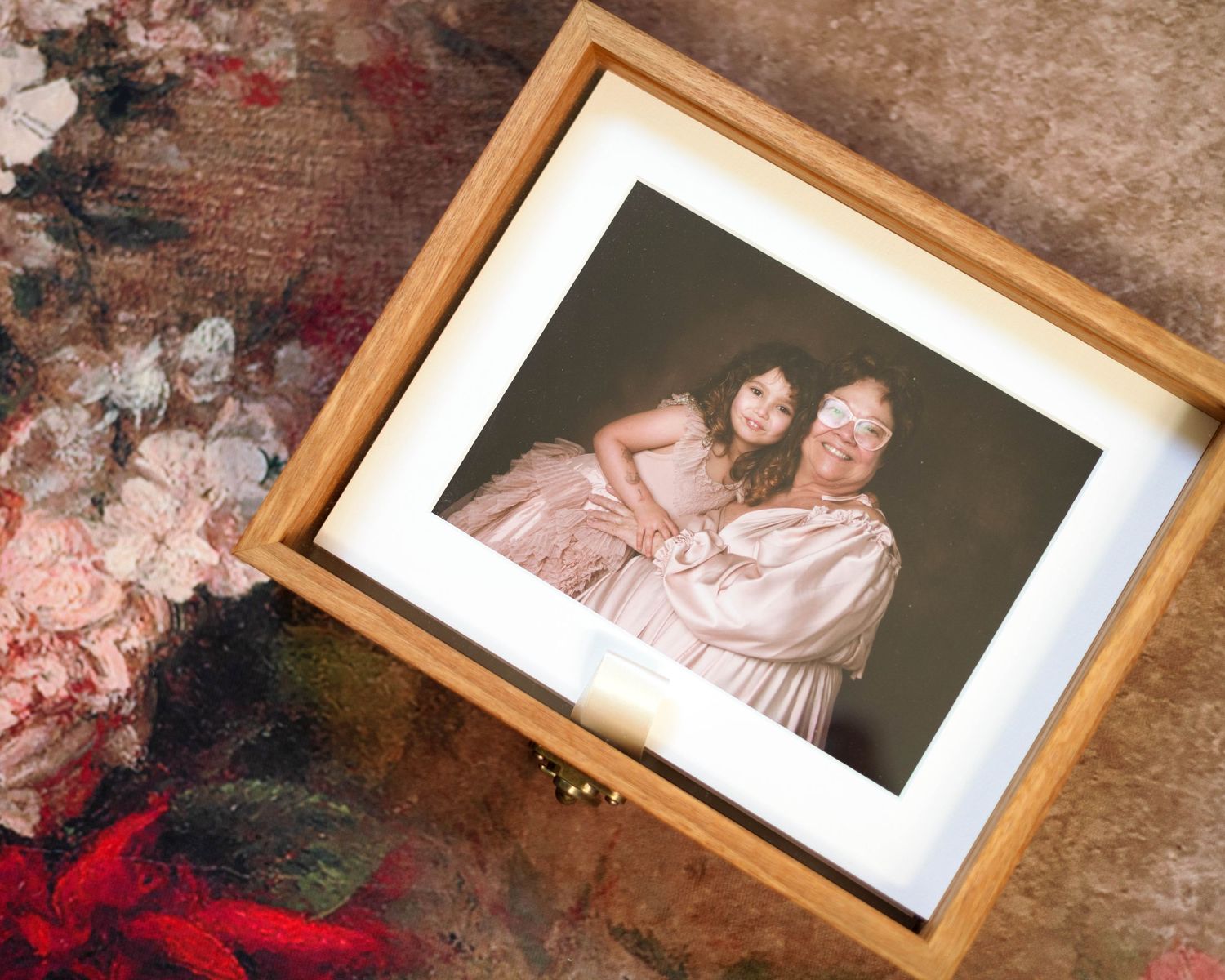 Multiple framed photographs on a textured concrete surface with a hint of red decor visible in the scene.