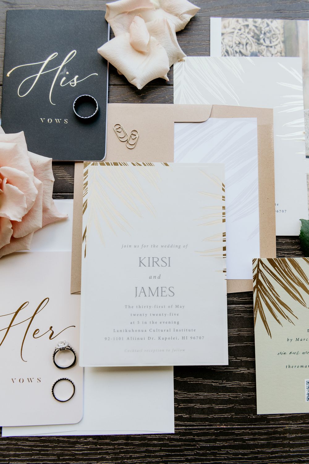 Wedding invitation suite featuring Kirsi and James names with vow books, rings, and peach roses on wooden surface.