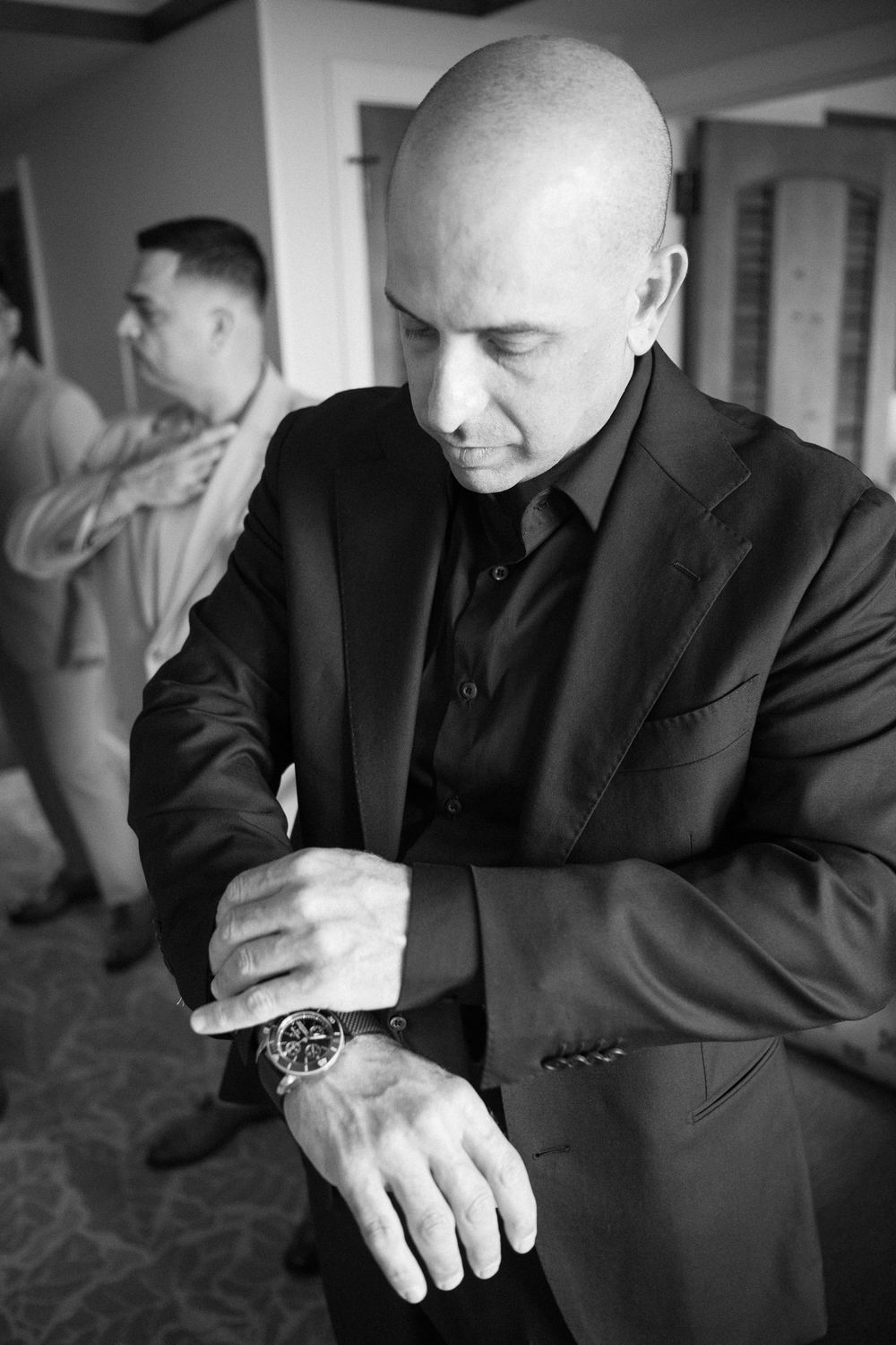 A black and white series of photos showing close-up details of hands and suits in various poses and gestures.