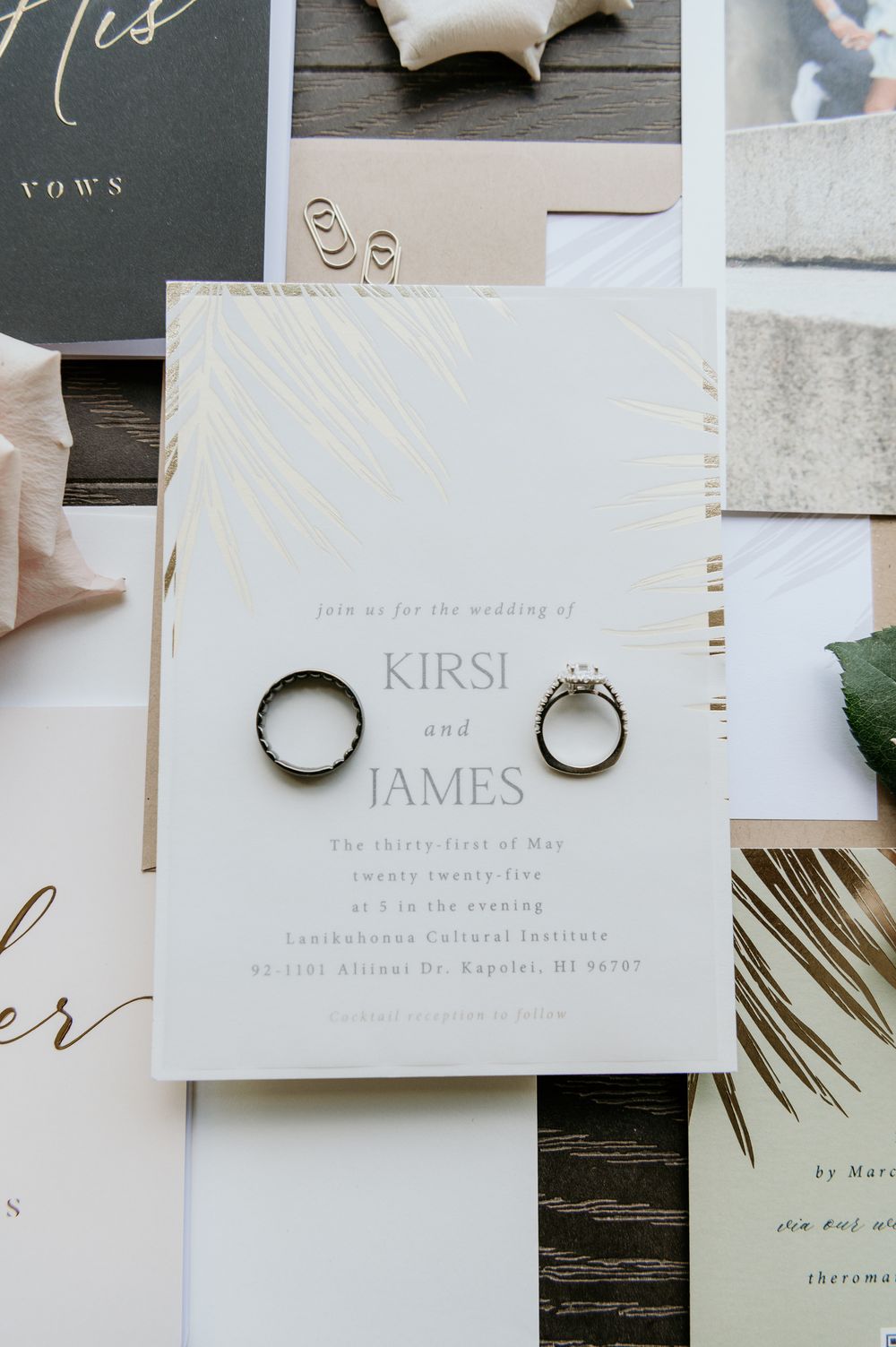 Wedding invitation with gold foil lettering and two silver wedding rings displayed on white stationery.
