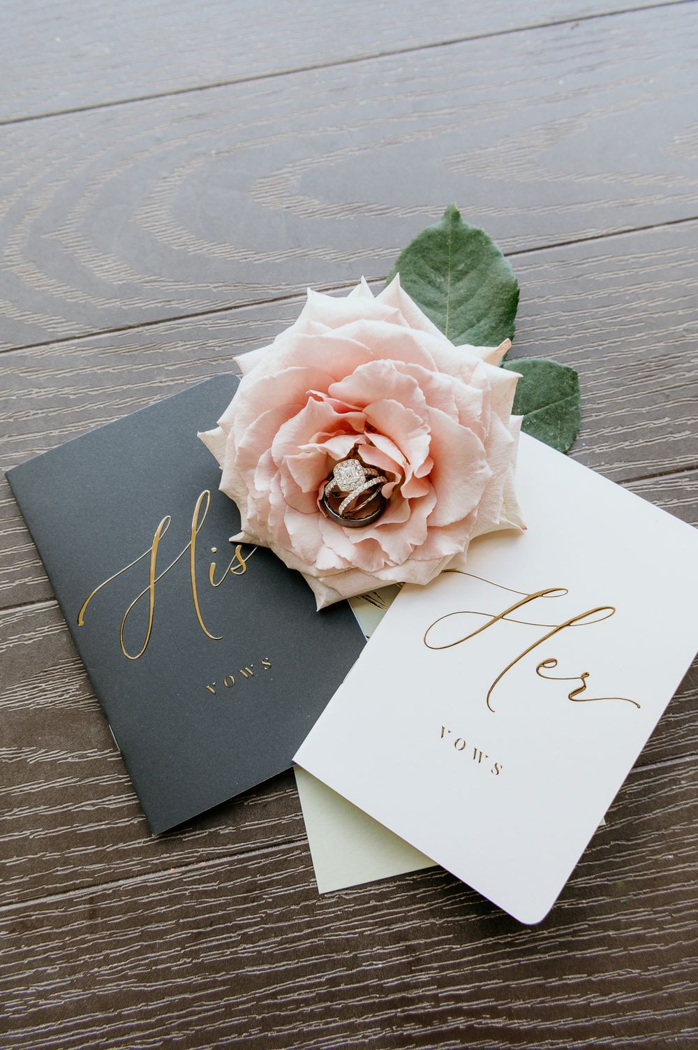 Pink blush rose adorns minimalist wedding place cards in black and white with elegant gold calligraphy lettering.