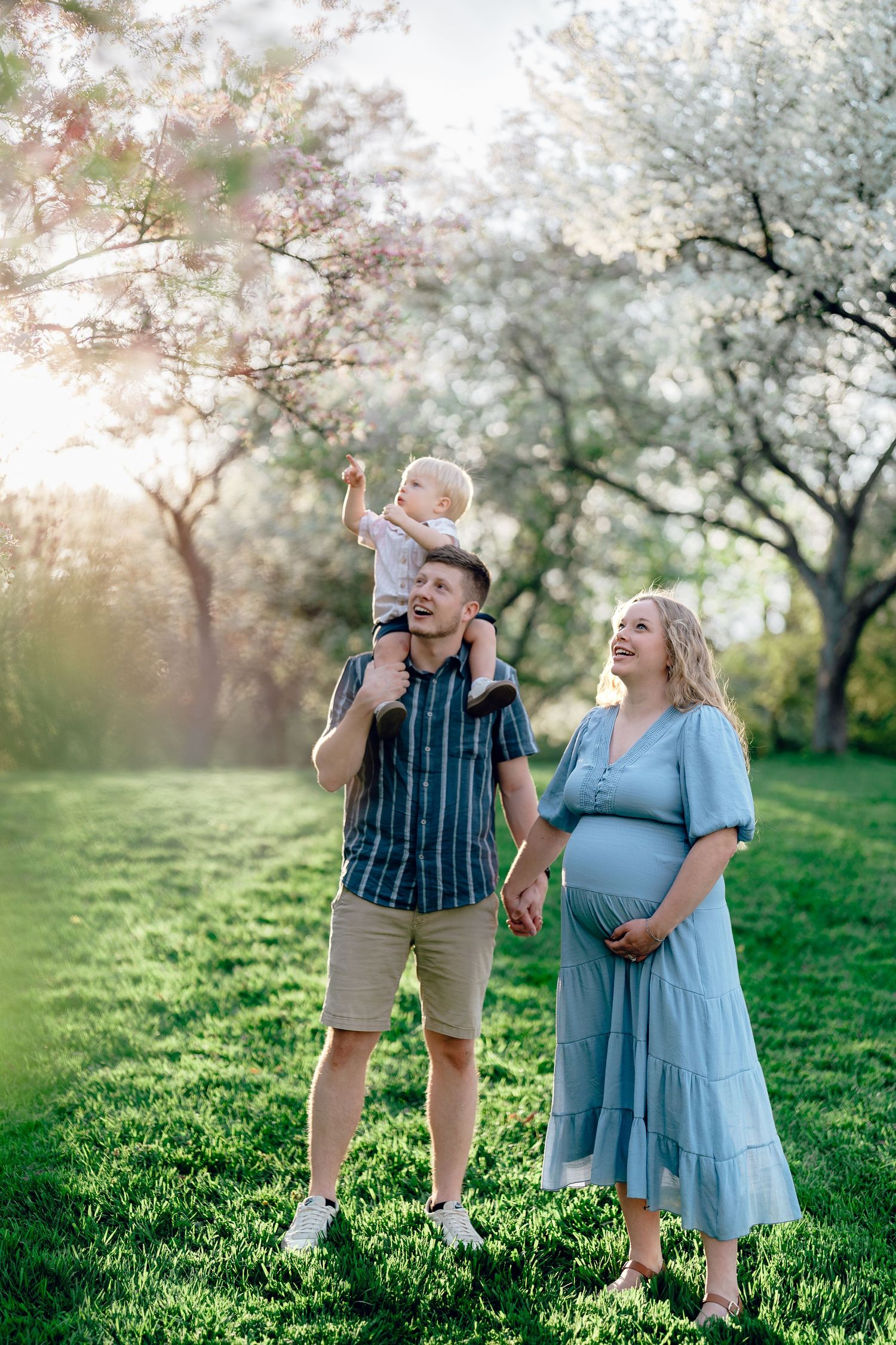 Two people share a joyful moment together under blooming spring trees during golden hour.