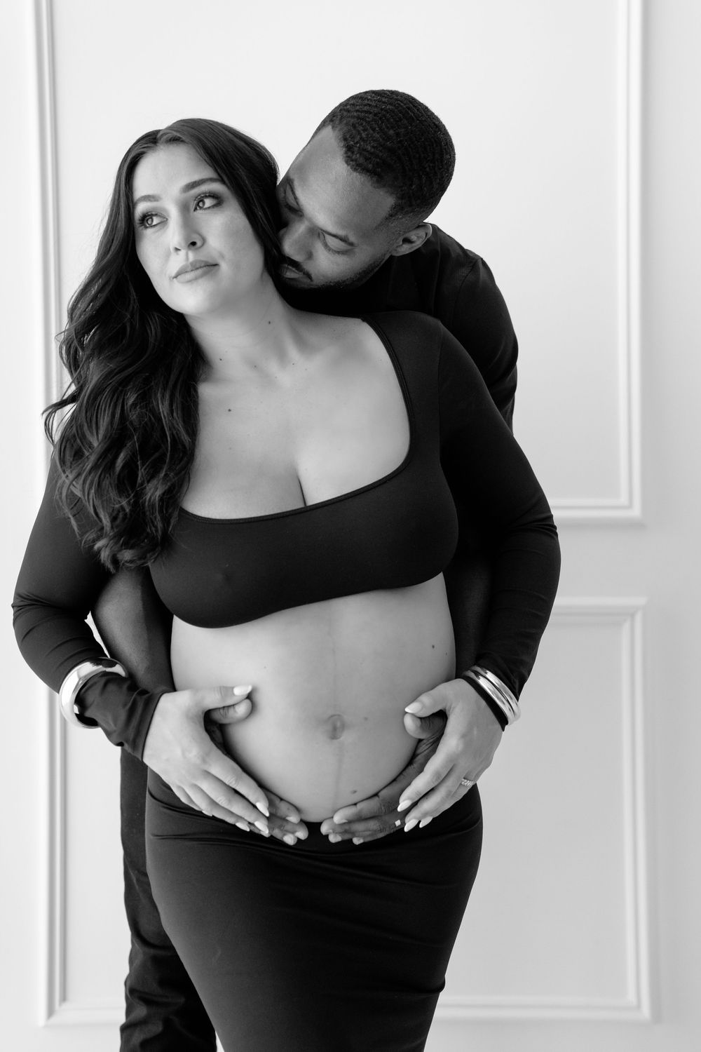 Black and white maternity portraits capturing intimate moments between an expecting couple.