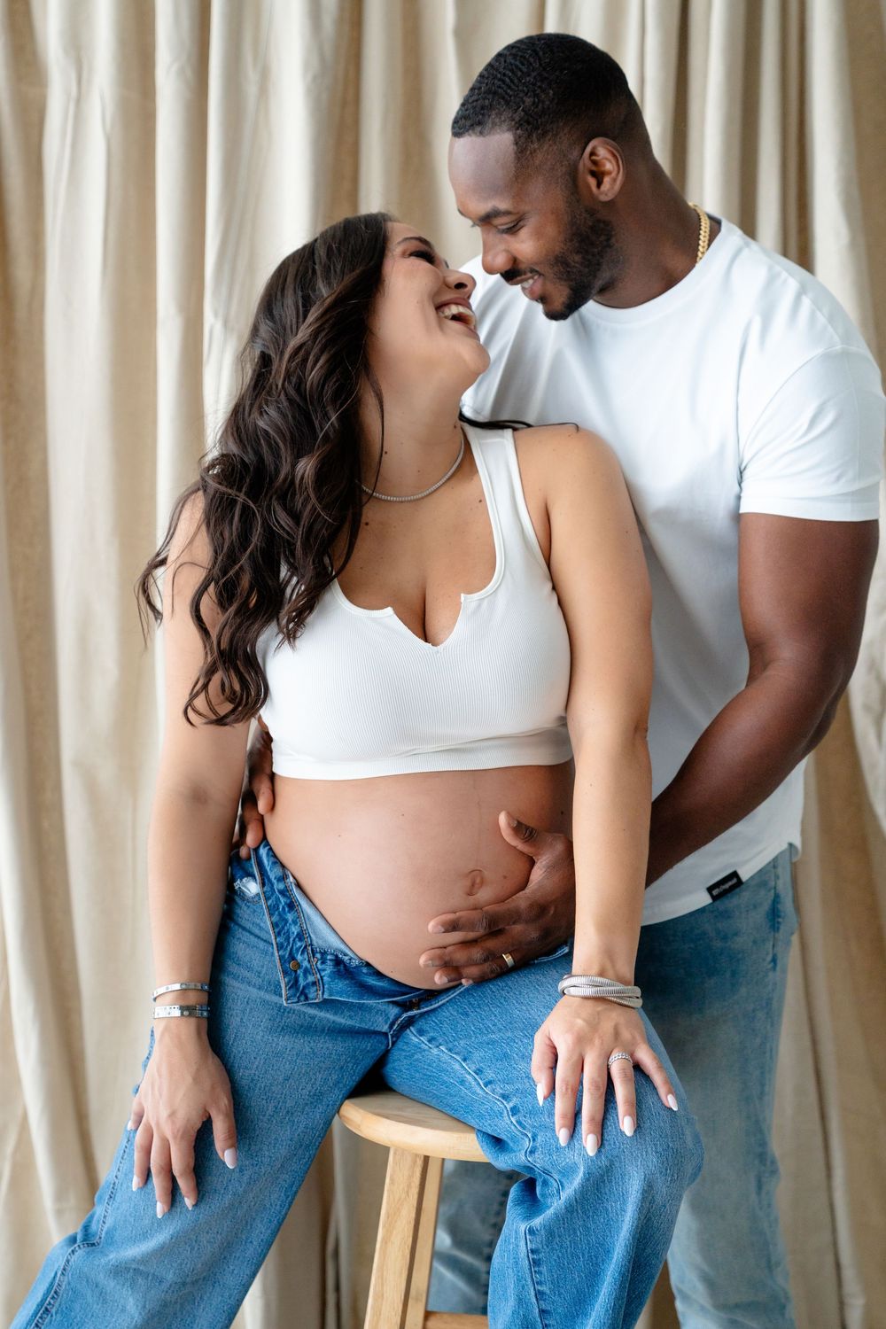 Intimate couple in jeans and white tops share romantic poses against curtained backdrop in collage-style photo series.