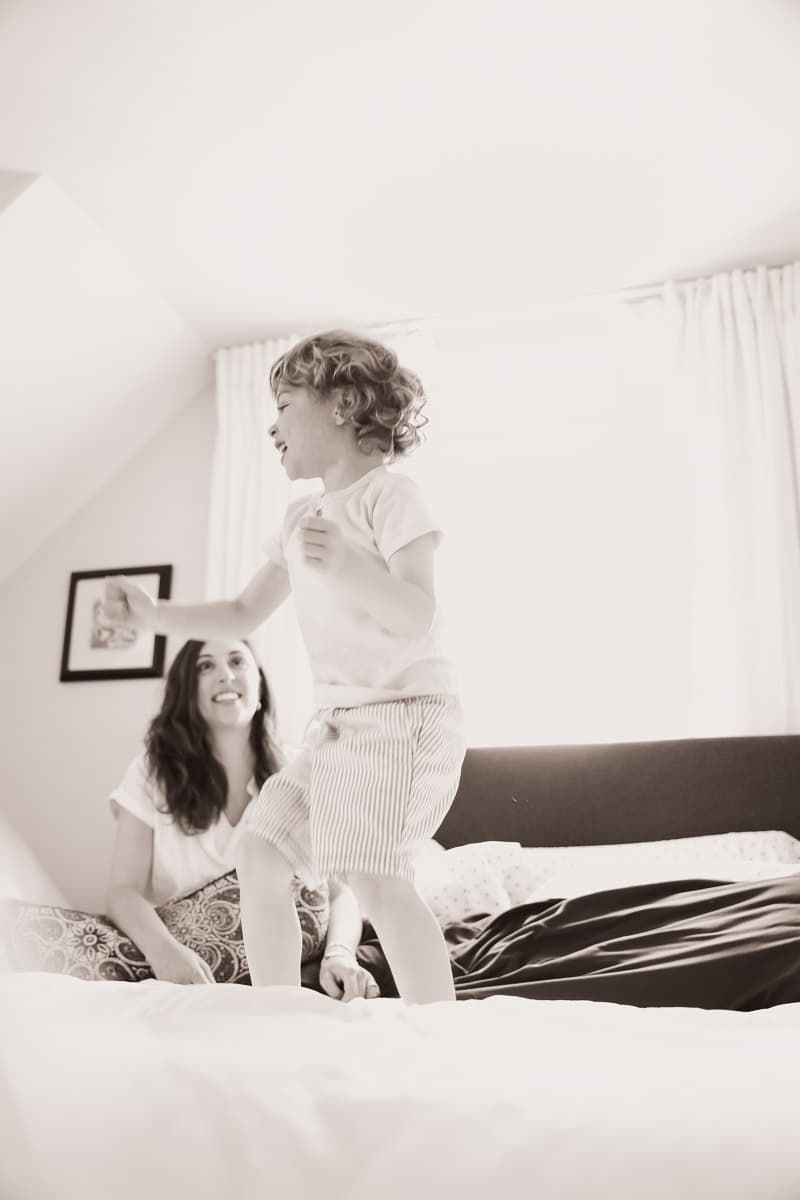 A series of soft black and white photos showing a child and parent sharing tender playful moments on a bed.