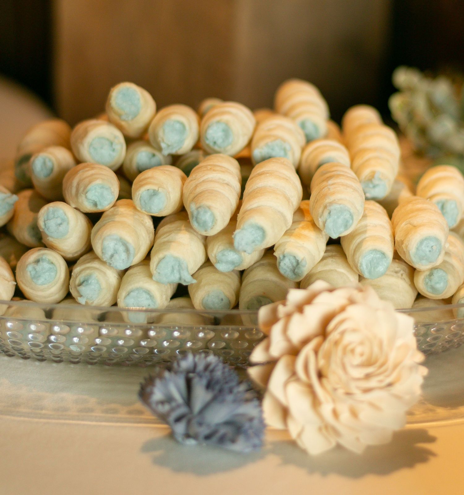 Classic wedding dessert display featuring rows of pastel cream puffs and elegant sugar flowers on a crystal cake stand.