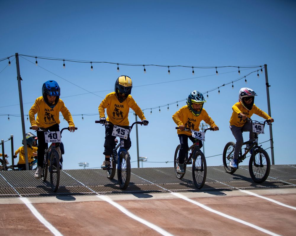 Multiple BMX racers lined up at starting gate on race track.