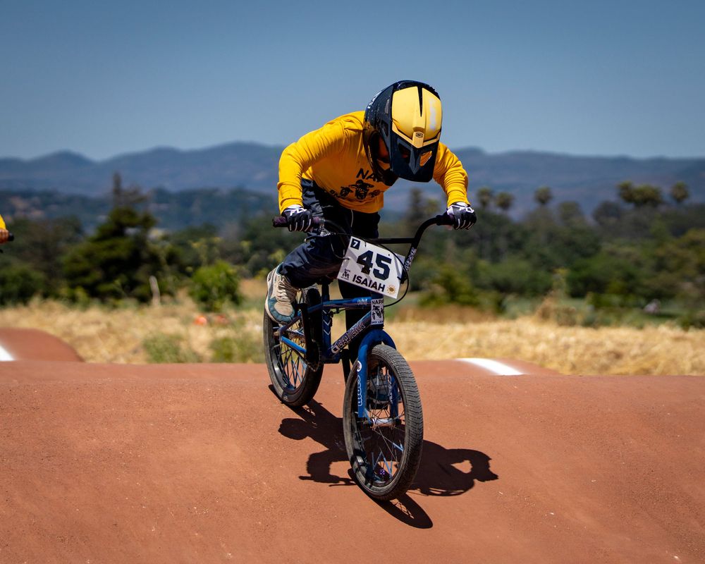 Sequence shot of BMX rider jumping over dirt track during race.