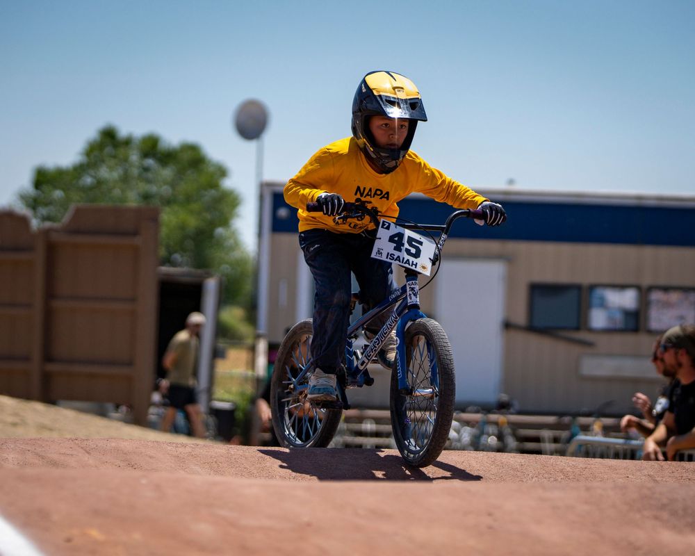 BMX racing action sequence on dirt track with clear blue sky background.