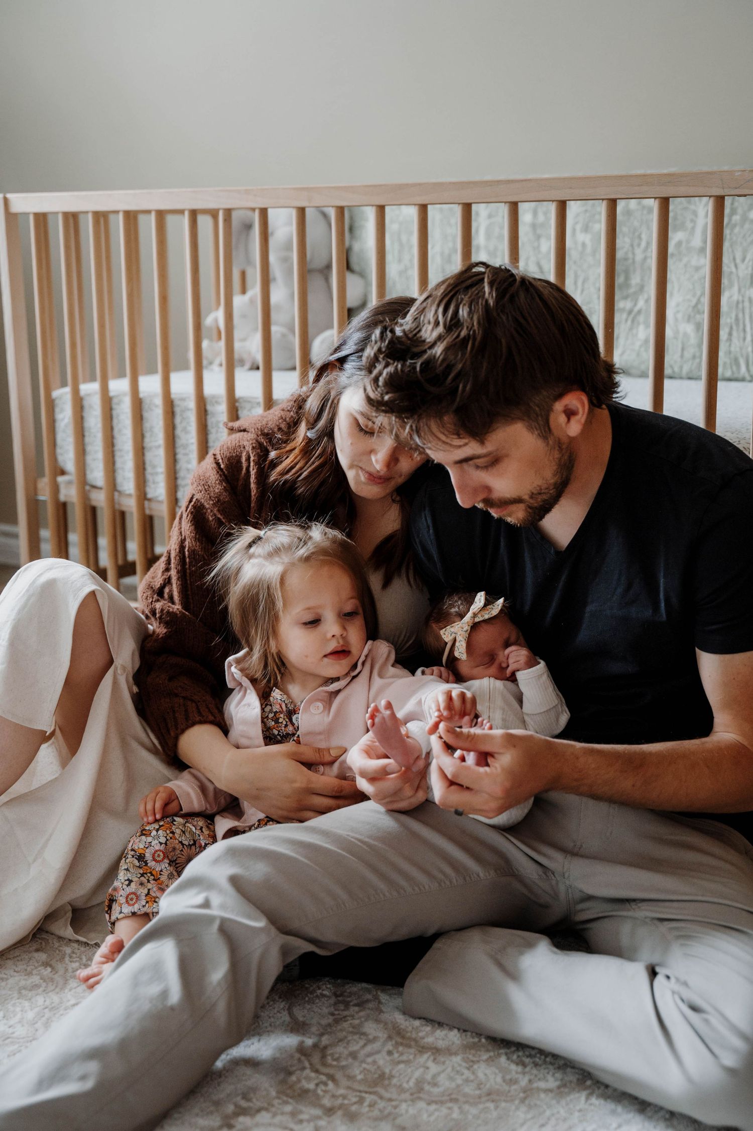 Intimate lifestyle family photo series showing tender moments between family members laying on white bedding.
