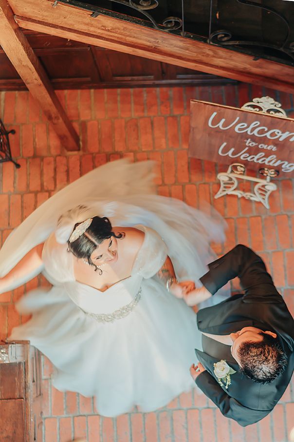 A couple dancing together in formal attire with the bride's white dress flowing elegantly in a rustic brick venue.