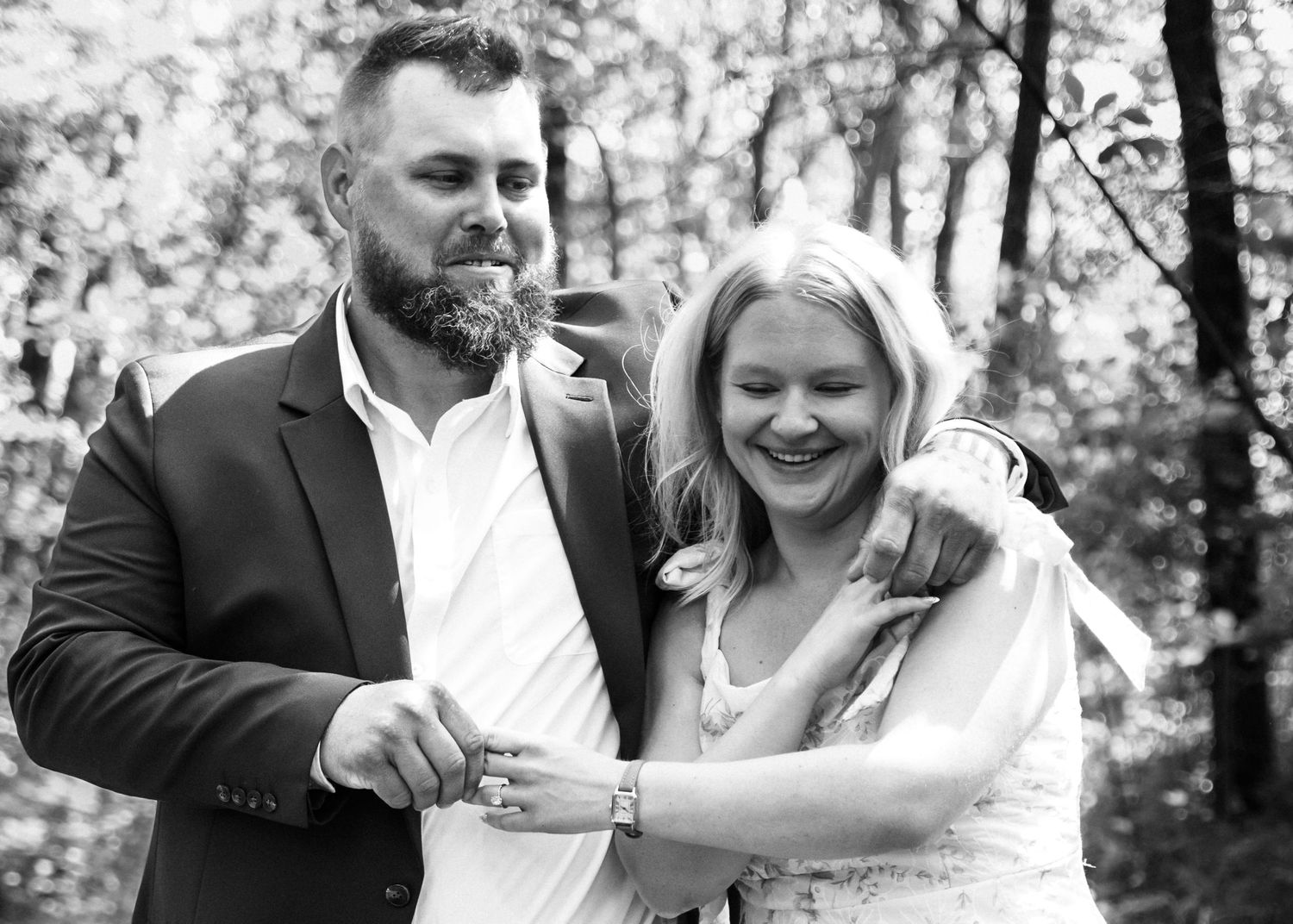Black and white, couple walking with his arm around her shoulders. Laughing at the goofy moment together walking in powell gardens