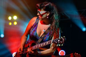 Band performing on stage with dramatic red and blue lighting during a high-energy rock concert.