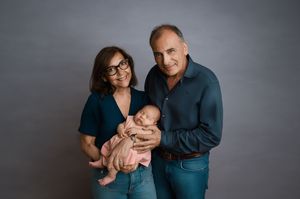 A couple in coordinated dark blue outfits posing together during a photo shoot showing tender affection.