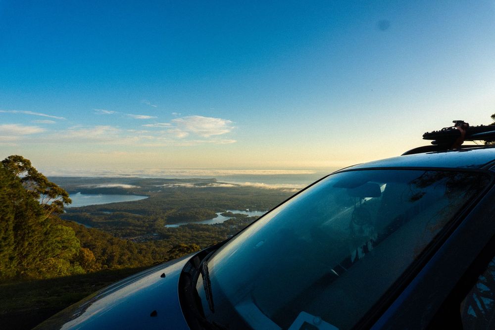 Panoramic aerial view of a coastal landscape with mountains and water during golden sunset lighting.